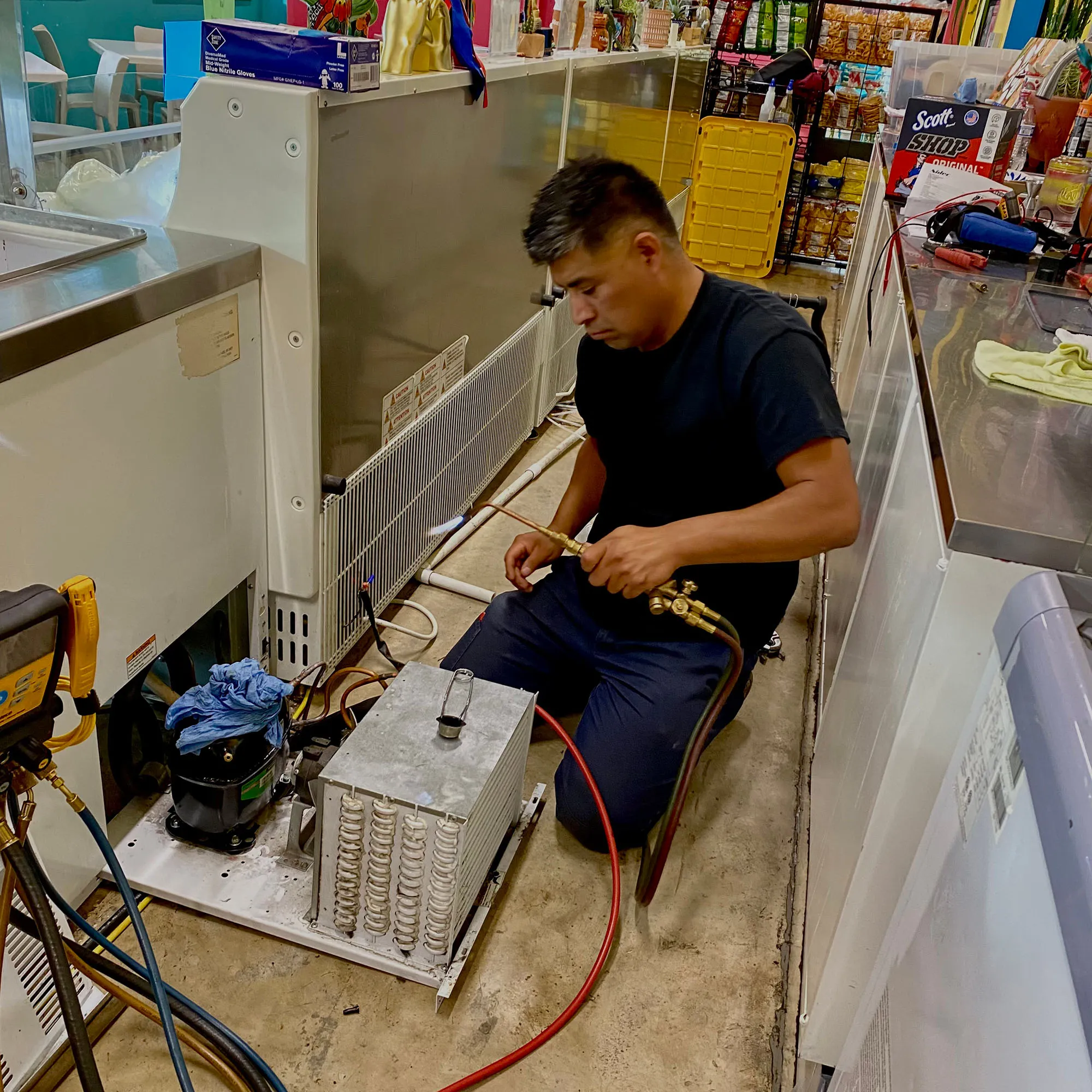 Pacific Breeze HVAC technician brazing a line on commercial refrigeration equipment in a restaurant