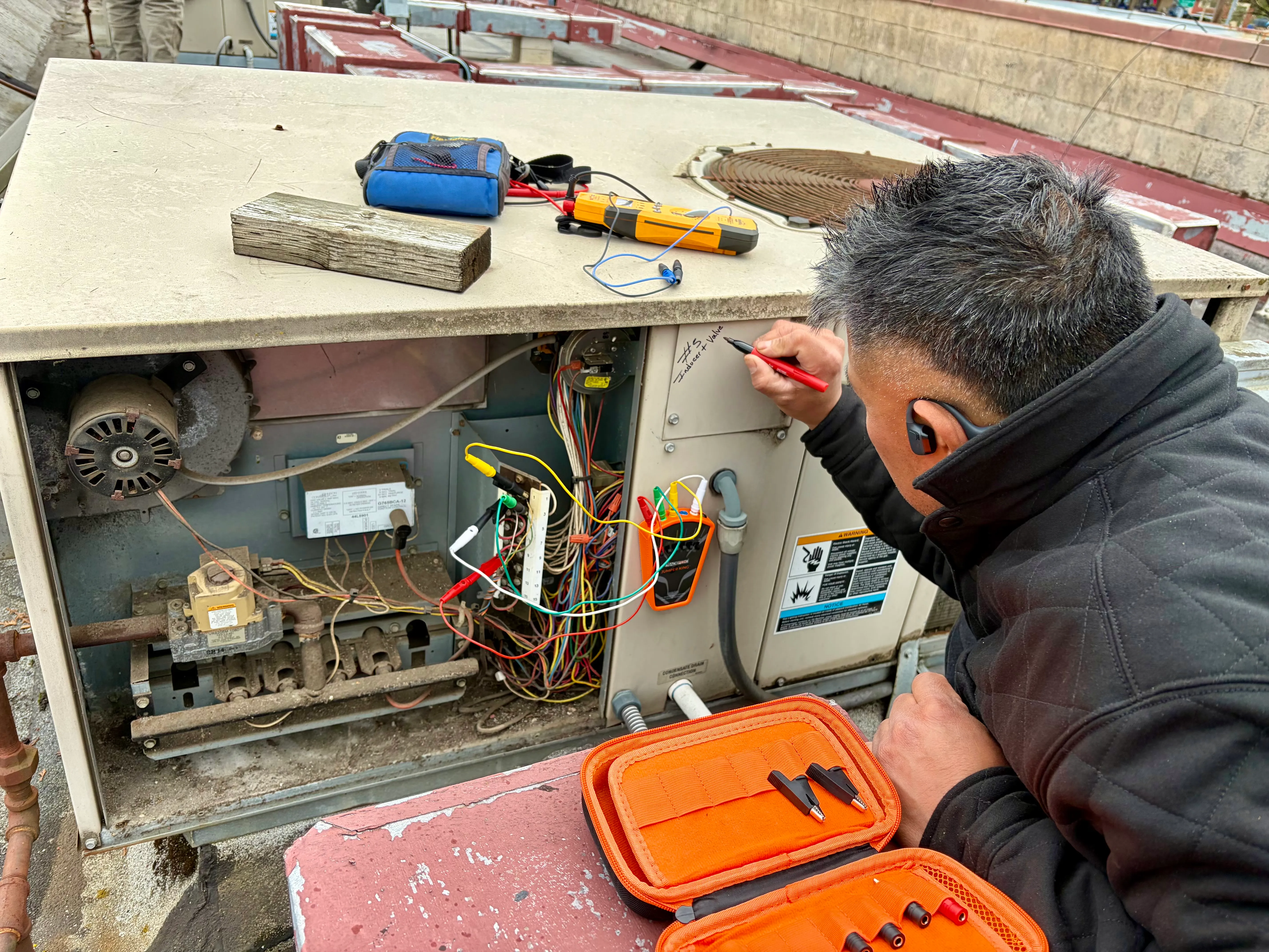 Pacific Breeze HVAC technician troubleshooting the wiring on a commercial rooftop HVAC unit
